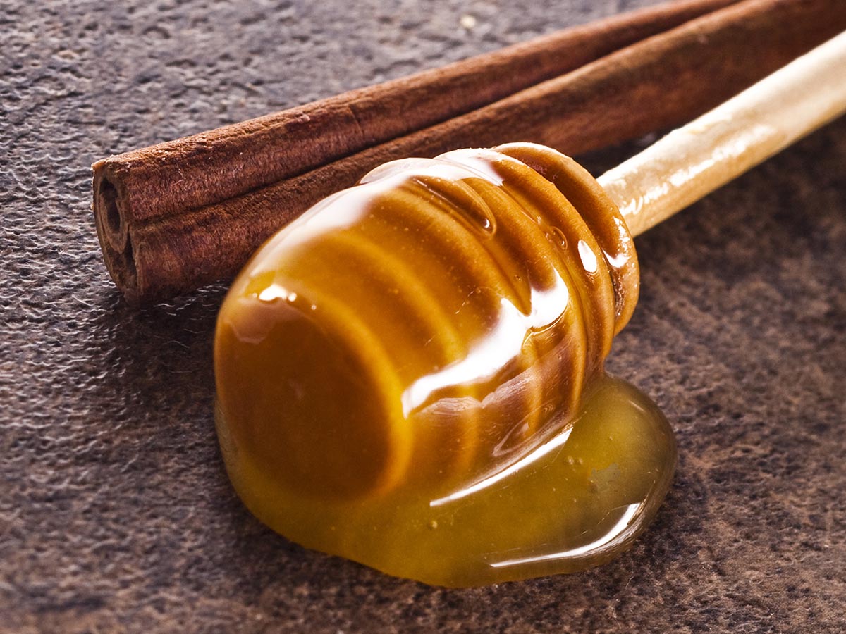 Cinnamon stick next to honey dipper covered in honey